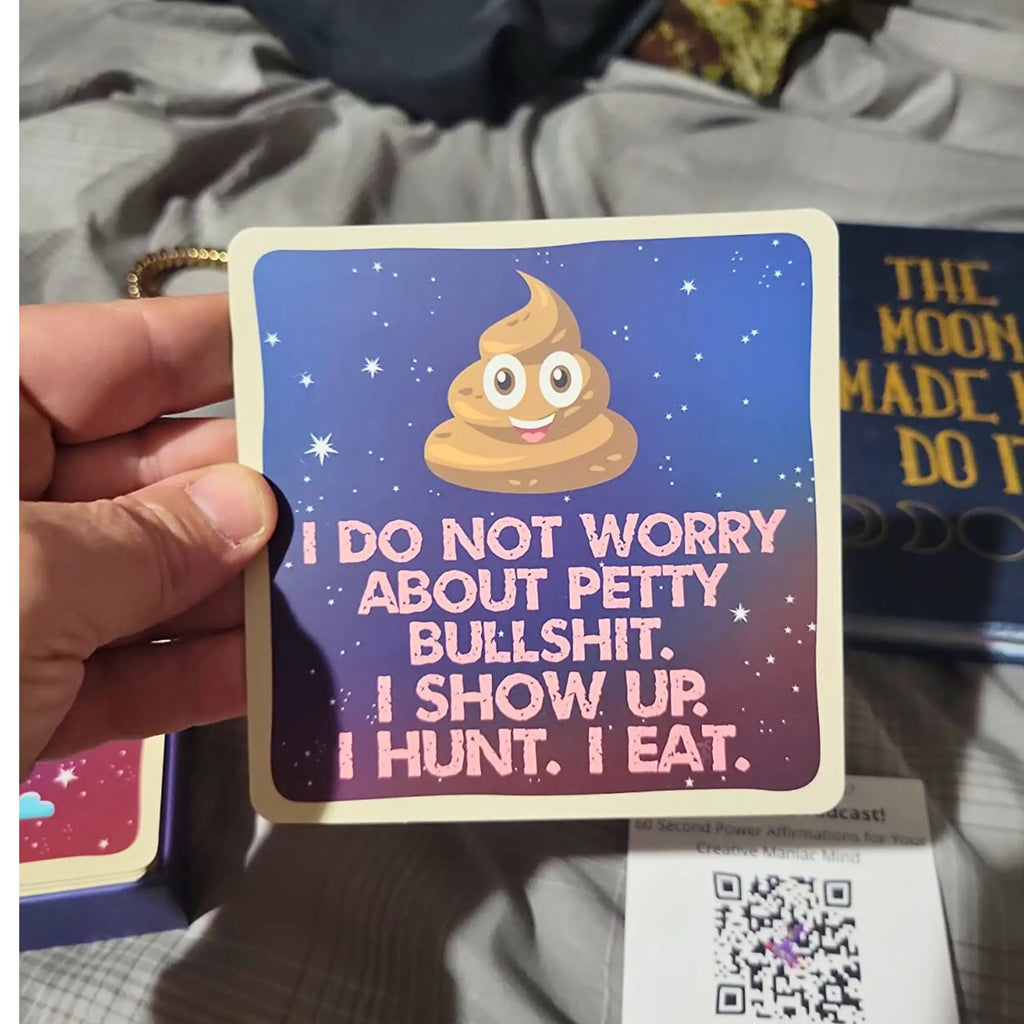 Card with a cartoon poop emoji and text held by a hand on a fabric background