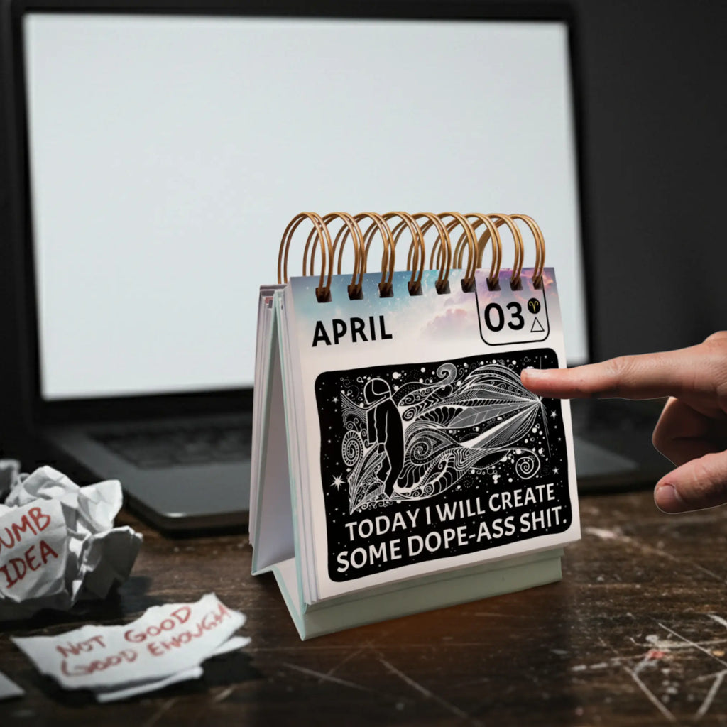Desk calendar with a humorous quote on a desk next to a laptop