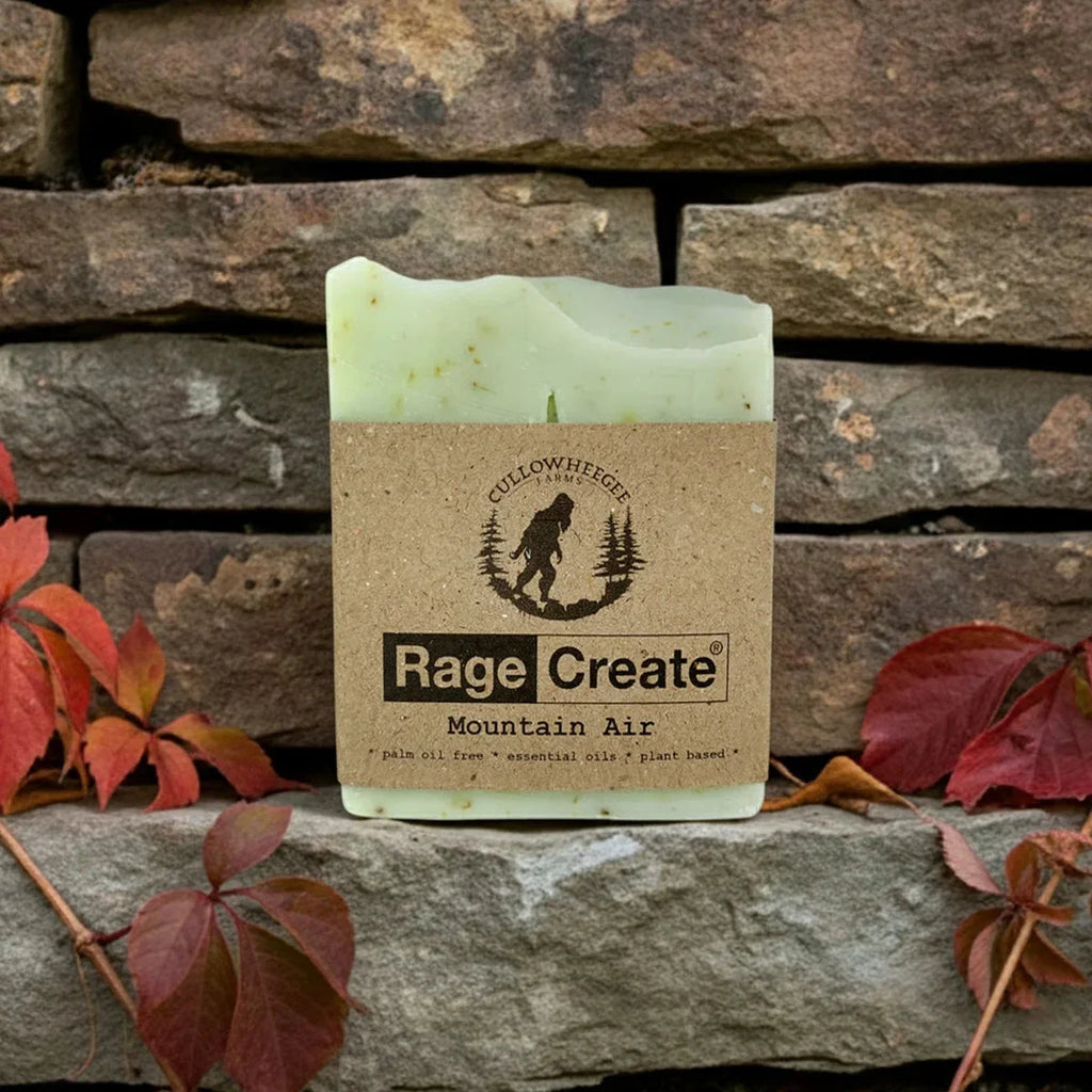 Pale green Rage Create Mountain Air soap bar with kraft paper label featuring Cullowhegh Farms branding, displayed on rustic stone brick wall surrounded by burgundy and orange autumn leaves.