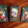 Oracle of the Magical Fairy Forest deck displayed on warm wooden surface with two green guidebooks flanking an ornate tarot card titled The Portal, featuring mystical fairy artwork with glowing lights