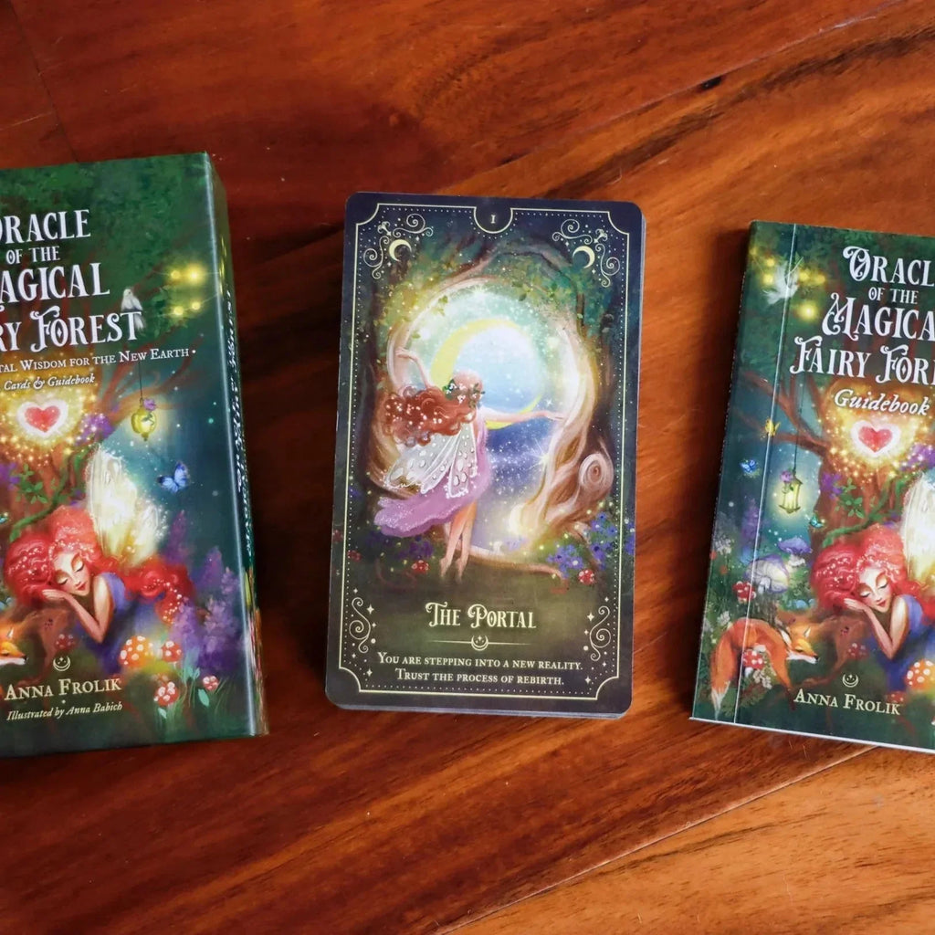 Oracle of the Magical Fairy Forest deck displayed on warm wooden surface with two green guidebooks flanking an ornate tarot card titled The Portal, featuring mystical fairy artwork with glowing lights