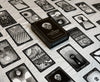 Black and white oracle deck box labeled 'The Eigengrau Oracle Deck' centered among fanned tarot cards with intricate skull and geometric illustrations on a cream fabric background.