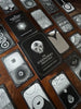 The Eigengrau Oracle Deck guidebook and black-and-white oracle cards arranged on a rich wooden surface, displaying intricate mystical imagery including skulls, eyes, and geometric patterns.