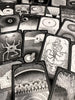 Black and white oracle cards scattered in an overlapping arrangement, featuring surreal detailed illustrations including eyes, hands, skulls, and cosmic patterns on dark borders with numbered labels.